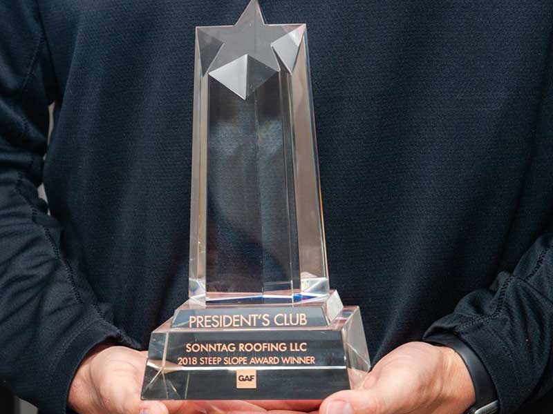 Close up of hands holding a GAF President's Club 2018 Steep Slope Award Winner trophy